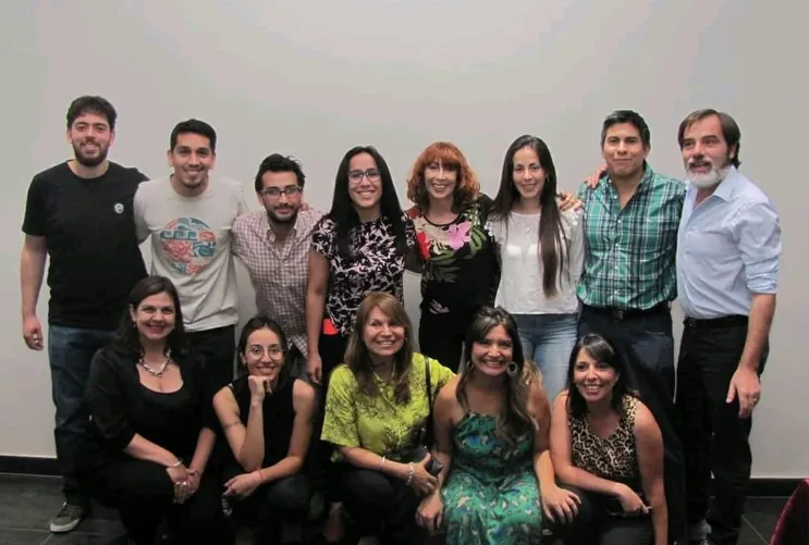 Grupo de investigadores del IISE-UNSJ posando frente a una pantalla durante la presentación de su libro sobre megaminería en San Juan.