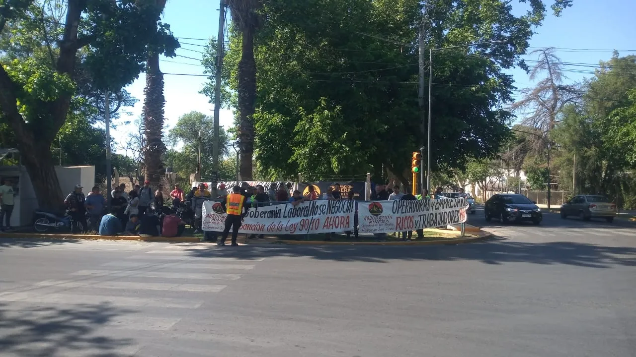 Grupo de trabajadores mineros desempleados de San Juan, Argentina, con banderas y pancartas, manifestándose por empleo digno.