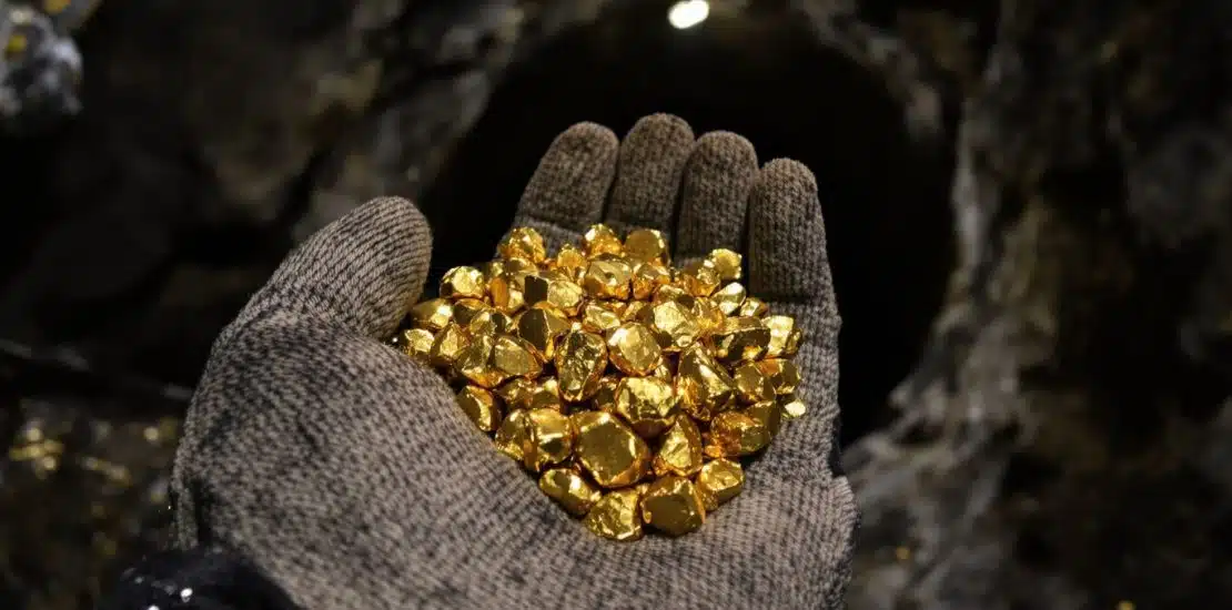 Minería en San Juan 2026: Mano sujetando pepitas de oro