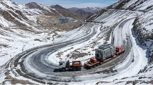 Camión minero circulando por camino de hielo en alta montaña.